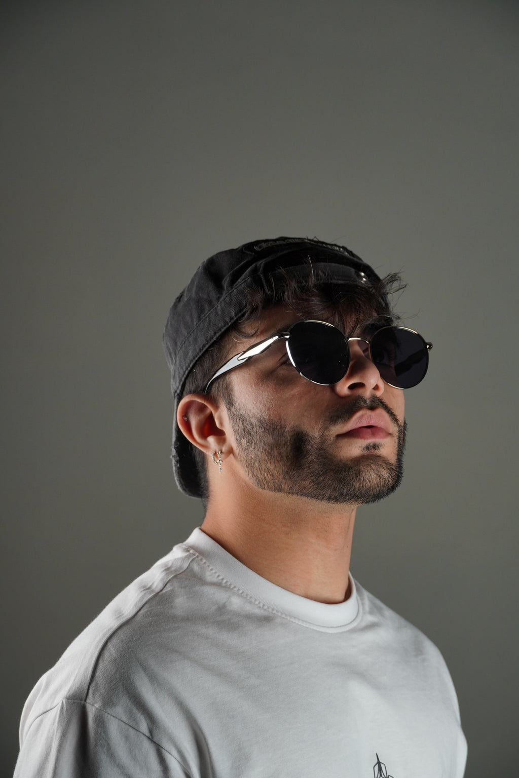Man wearing sunglasses and a cap against a gray background