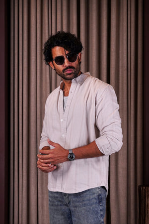 Man wearing sunglasses and a light shirt standing in front of a curtain